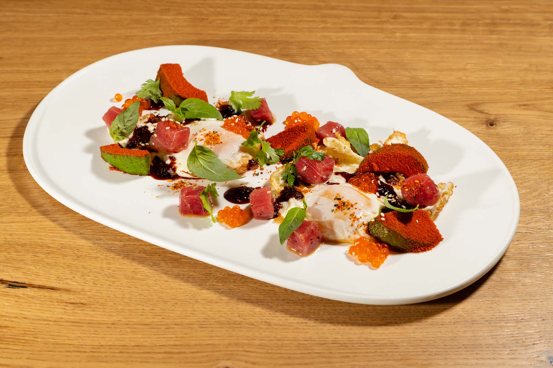 Huevos fritos ilustrados con atún, aguacate y huevas de salmón